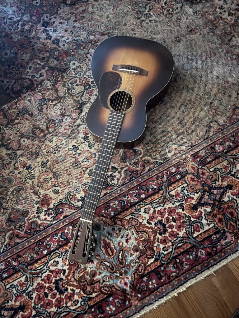 A vintage 1937 00-18H Martin guitar laying on a worn oriental carpet