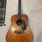 A 1941 D-18 guitar laying on a tiled floor