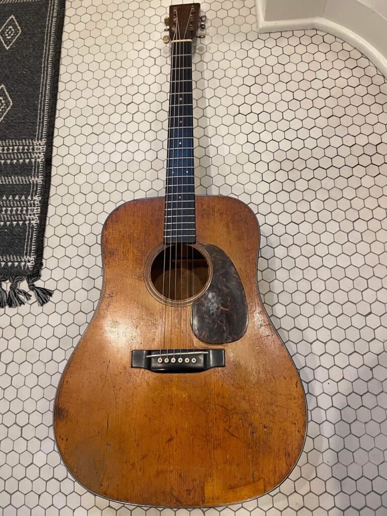 A 1941 D-18 guitar laying on a tiled floor