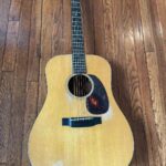 A 1941 D-18 guitar laying on a wooden floor